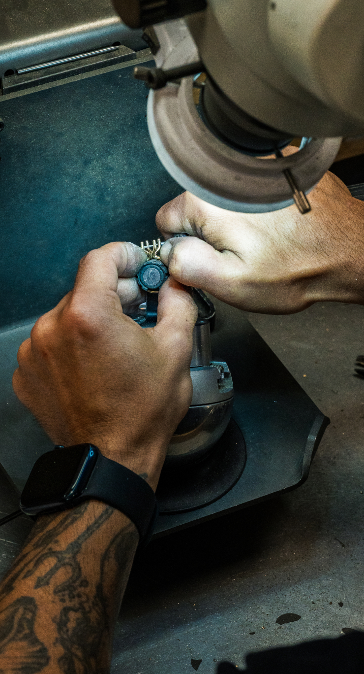Hands setting a diamond into a custom engagement ring at the workbench